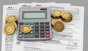 Tax forms under a calculator and golden Bitcoins